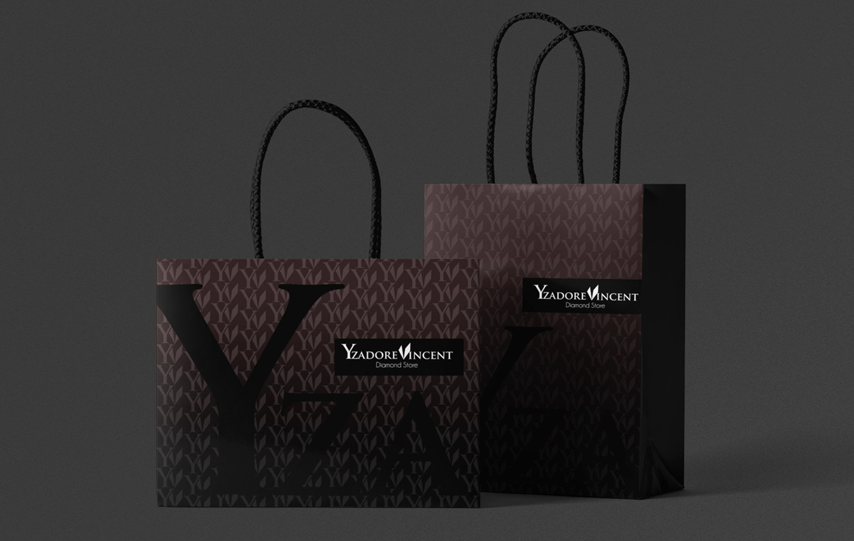 Jeweler Branding Giftbag Two dark chocolate-brown shopping bags with braided rope handles and a subtle repeating monogram pattern, photographed against a charcoal background as packaging for jewelry branding.