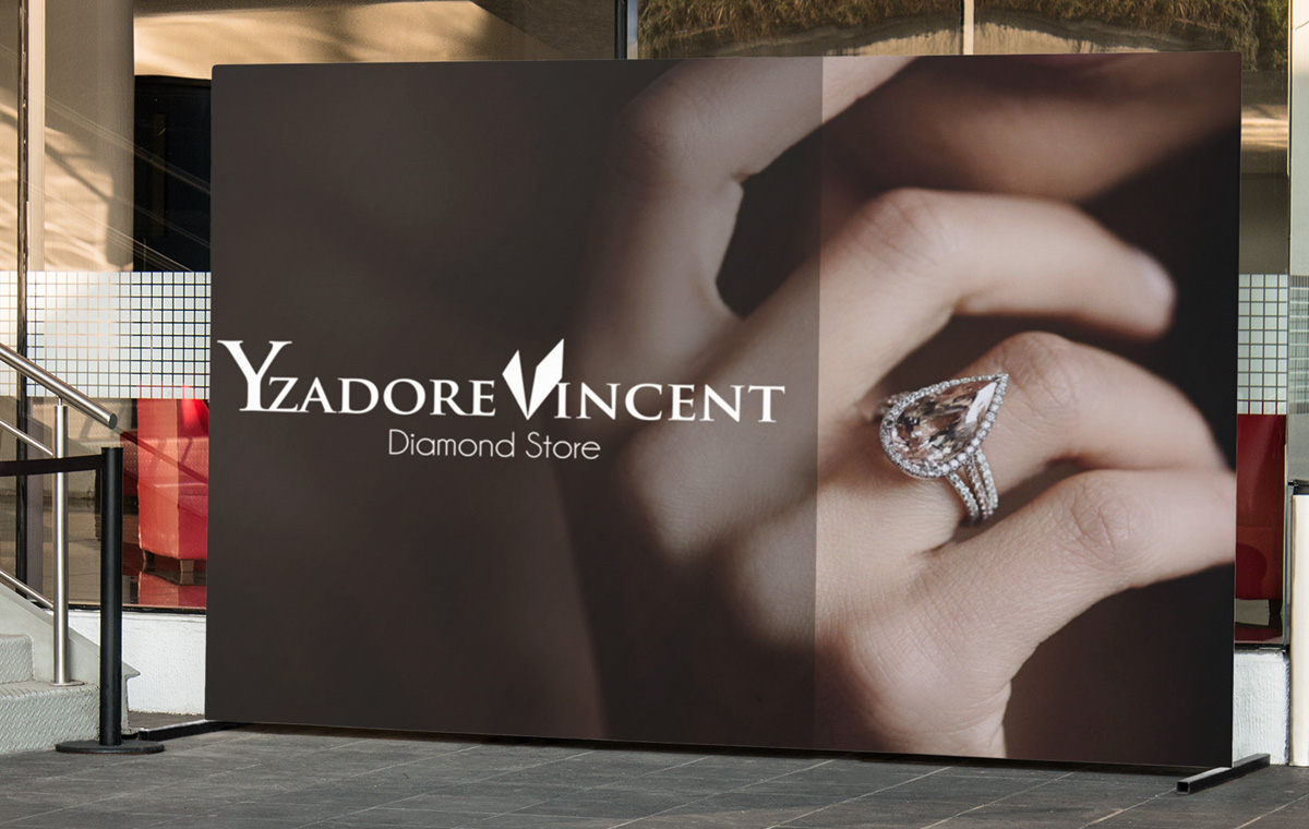 Jewelery Store Brand Design Freestanding fabric banner display outside a glass storefront showing a woman's hand wearing a large pear-shaped halo ring in soft warm lighting, an elegant retail application of jewelry branding.