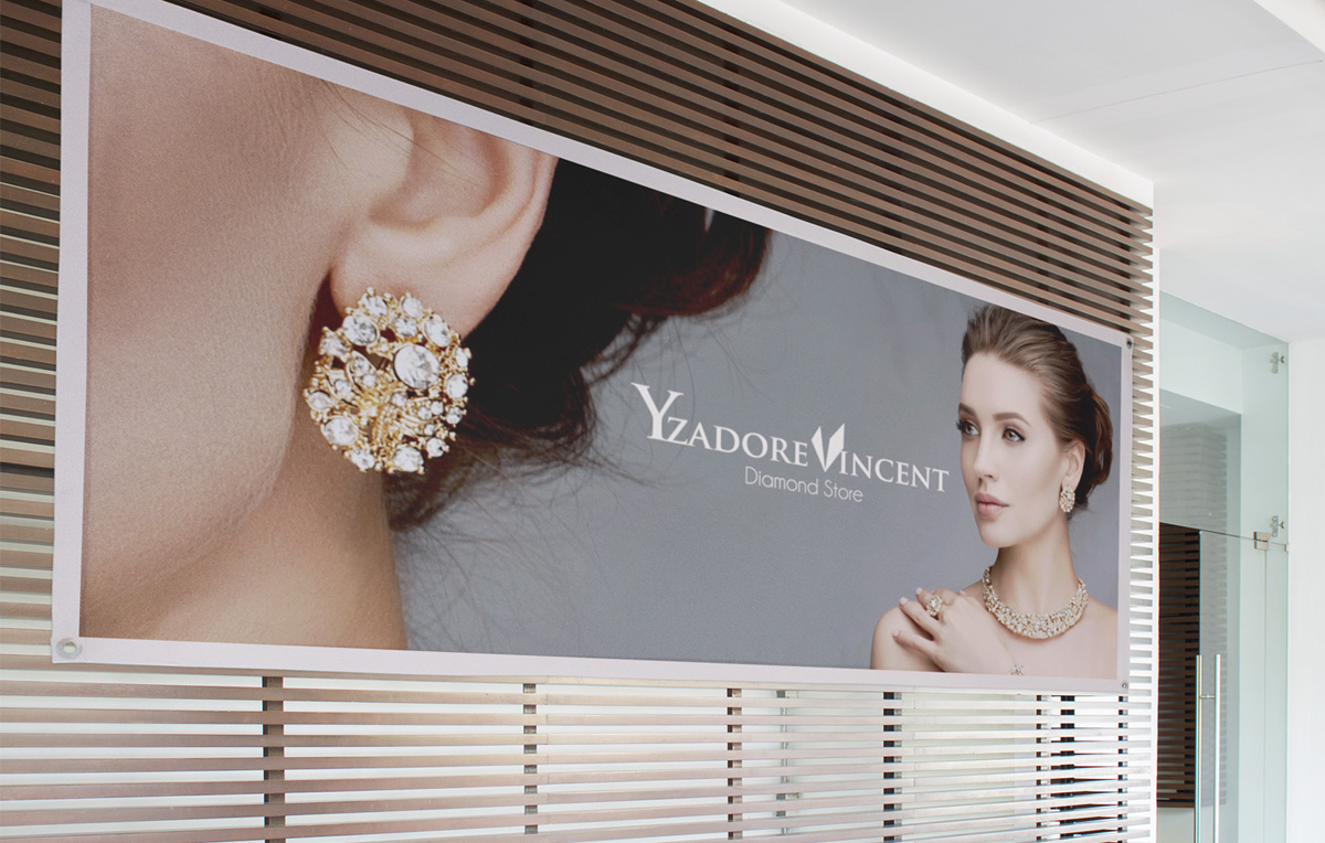 Jewlery Store Branding Wide interior wall banner mounted on a wood slat panel, showing a close-up gold cluster earring on a woman's ear alongside a model in matching necklace and ring, an upscale in-store use of jewelry branding.