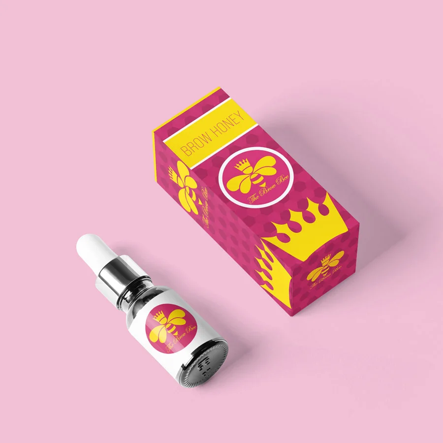 Omaha Branding Services for Beauty Products Omaha branding services packaging mockup showing a dropper bottle beside a matching pink honeycomb-patterned box decorated with a crowned bee logo, set against a soft pink background.