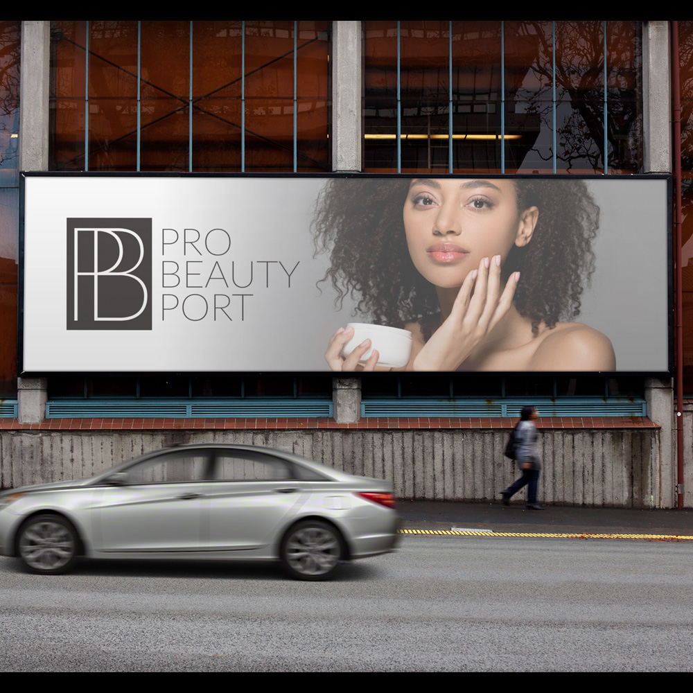 Omaha Logo Designer for Hire A wide street-level billboard on a brick building displays a monogram mark beside a woman with curly hair holding a small round jar of cream against her cheek, an outdoor advertising mockup created by an Omaha logo designer.