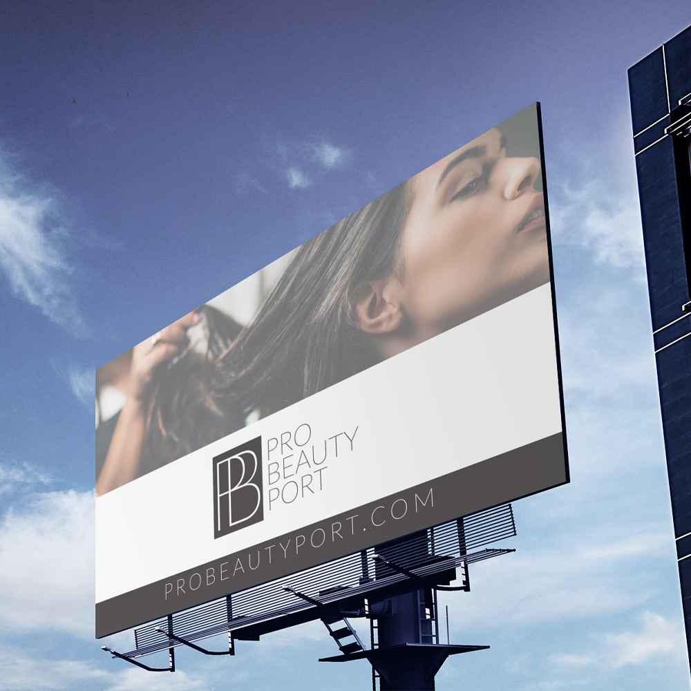 Omaha Logo Designer for Hire A large highway billboard against a bright blue sky shows a woman running her fingers through long glossy hair above a monogram mark and web address bar, a beauty branding mockup from an Omaha logo designer.