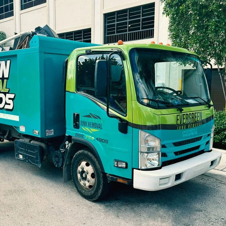 evergreen-junk-removal-truck-wrap Green and teal Evergreen Junk Removal truck parked outside a commercial building.
