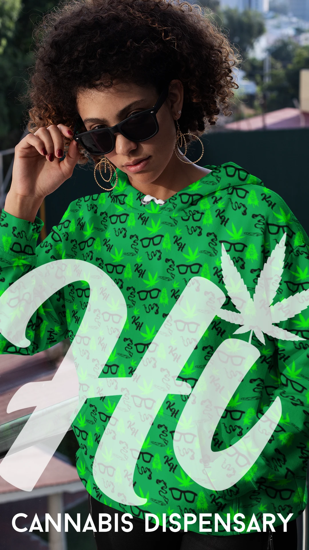 kooley-hi-cannabis-hoodie-woman-model Woman modeling a green Kooley Hi cannabis dispensary hoodie with logo pattern.