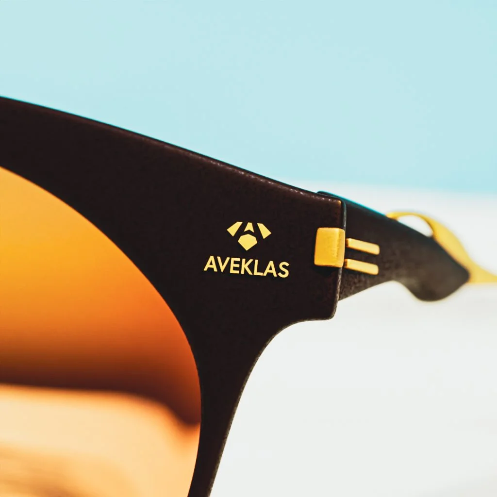 sunglasses-temple-logo-detail Close-up of a sunglasses arm showing an engraved gold brand logo detail