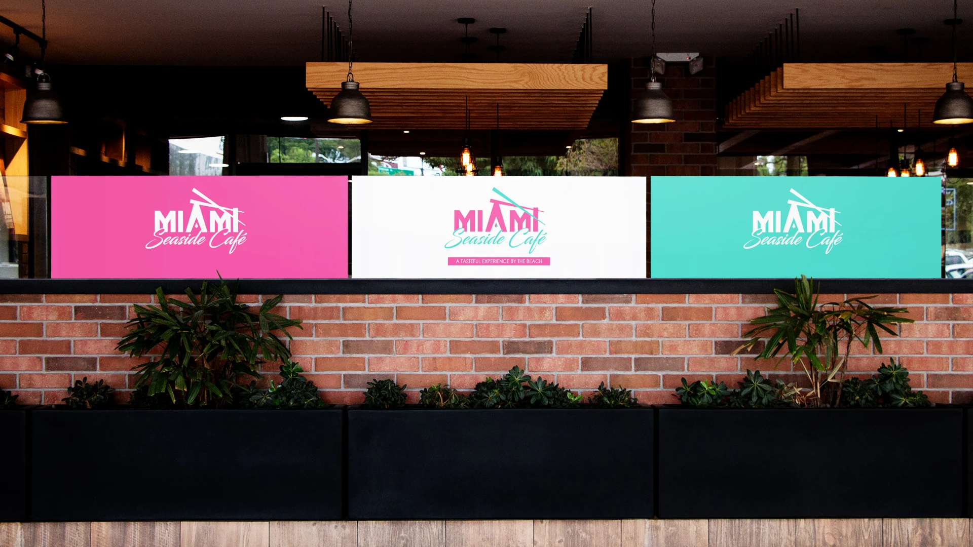 restraurant branding design signage Three Miami Seaside Café signs in pink, white, and teal above a brick planter wall, each showing the logo